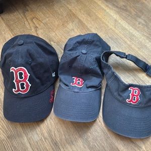 Lot of Boston Red Sox hats and a visor.